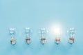 Top view of light bulbs in row and one of them glowing on blue background, Royalty Free Stock Photo