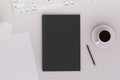 Top view of light workplace with empty black notepad, pen and coffee cup. Workspace concept.