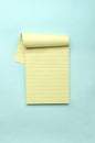 Vertical image.Top view of yellow lined notebook on the light blue background.Empty space