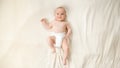 Top view of little baby boy in diapers lying on soft white blanket on bed. Royalty Free Stock Photo