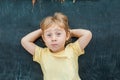 Top view of a little blond kid boy with space for text and symbols on the old wooden background. Concept for confusion