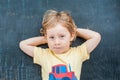 Top view of a little blond kid boy with space for text and symbols on the old wooden background. Concept for confusion