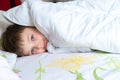 Top view of little boy in bed covering his face with white blanket or coverlet. Sleeping boy Royalty Free Stock Photo