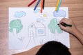 Top view of a little boy drawing a house with crayons is a beautiful imagination painting. A child`s hand is engaged in creativit Royalty Free Stock Photo