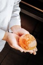 Top view of little bun topped with sesame seeds in hands of baker