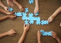 Top view of little children playing puzzle together at table, focus on hands