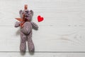 Top view of little cute teddybear and red wooden heart on wooden background. Copy space for esign. Love holiday concept