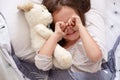 Top view of little girl cry in bed with teddy bear, toddler laiyng on linens with dandelion, charming kid rubbing her eyes after Royalty Free Stock Photo