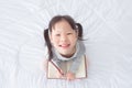 Little girl holding notebook and smiles on bed Royalty Free Stock Photo