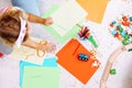 Top view of little girl standing on all fours, holding green pencil around coloured pencils, toys, puzzles in classroom. Royalty Free Stock Photo