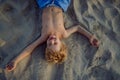 Top view of little playful boy lying on the beach.