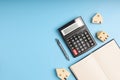 Top view LOAN on the black calculator with little home models, notebook, and white piggy bank on blue background with copy space. Royalty Free Stock Photo