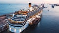 Top view of the luxury cruise ship upper deck near the pier with many people on board relaxing, playing basketball and