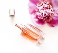 Top view of luxury perfume bottle and pink peony flower on white background. Female cosmetic and makeup accessory still life