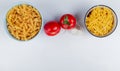 top view of macaronis as rotini and tagliatelle with tomatoes and garlic on white background with copy space Royalty Free Stock Photo