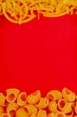 top view of macaronis as tagliatelle and pipe-rigate on red background with copy space