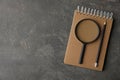 Top view of magnifier glass, notebook and pencil on grey stone background, space for text. Find keywords concept Royalty Free Stock Photo