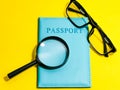 Top view magnifying glass with passport and eye glasses isolated on yellow background.