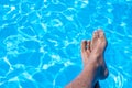 Top view of male feet against the blue water of the swimming pool Royalty Free Stock Photo