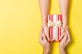 Top view of male and female hands holding present box on colorful background. Sharing a gift concept. Close up