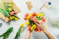 Top view male florist hands making spring bouquet using tulips at workspace with recycled wrapping materials. Learning flower Royalty Free Stock Photo