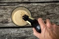 Top view of male hand pouring dark beer in a glass