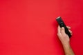 Top view of male hand, black tv clicker for smart television onth red surface.Empty space Royalty Free Stock Photo