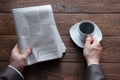 Top view on male hands holding a German newspaper and a cup of black coffee. Reading the news in the morning. Finance, business. Royalty Free Stock Photo