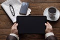 Top view on male hands holding a tablet, a cup of coffee and a morning newspaper. Work is all office. Business concept. Place for Royalty Free Stock Photo