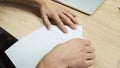 Top view of male hands trying to make a plane from a sheet of paper. Stock footage. Close up of man hands practicing Royalty Free Stock Photo