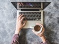 Top view of Male hands working on Laptop and holding a coffee cup with grunge gray background. Royalty Free Stock Photo