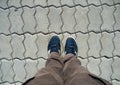 Top view of male legs in brown trousers and blue sneakers