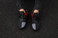 Top view on male legs in trendy sneakers on a black background. Young stylish man in jeans in sports fashionable red-black shoes. Royalty Free Stock Photo