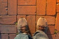 Top view of a male`s worn out sneakers standing on a brick path Royalty Free Stock Photo