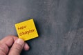 Top view of man hand holding yellow board written with text NEW CHAPTER Royalty Free Stock Photo