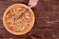 Top view of man hand which cutting the pizza with a kitchen knife. Delicious pizza with chicken breast, corn, bacon and mushrooms Royalty Free Stock Photo