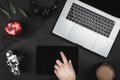 Top view man hands typing on a tablet screen, on dark desk is keyboard laptop, headphones, camera, a coffee mug and red apple Royalty Free Stock Photo