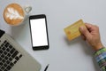 Top view of a man holding a credit card Mobile phone mock up blank white screen and computer and coffee Business communication Royalty Free Stock Photo