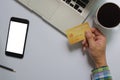 Top view of a man holding a credit card Mobile phone mock up blank white screen and computer and coffee Business communication Royalty Free Stock Photo