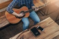 Top view of a man playing guitar with bible and smart phone on wooden table