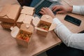 Top view of man\'s hands that is typing on the laptop. Food in the paper eco boxes are on the table