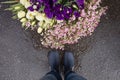 Top view on man`s legs in blue rubber boot standing close to a basket with beautiful garden flowers. after rain Royalty Free Stock Photo