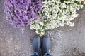 Top view on man`s legs in blue rubber boot standing close to a basket with beautiful garden flowers. after rain Royalty Free Stock Photo