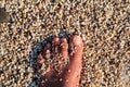 Top view of man standing bare feet on beach. Texture of bottom, leg and foot of man drowning with sweeping stone below on in sea.