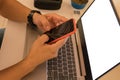 Top view of a man using a smartphone at a white desk. Blank screen laptop for graphical mounting