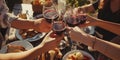 Top view many hands clink glasses with wine on a sunny day against the background of a table with blurred healthy food