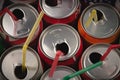 Top view of many opened aluminium cans of beer or soda with colorful straws inside them