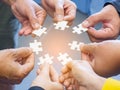 Top view of many people hands holding a jigsaw puzzle piece in a circle together with sunlight effect. Concept of teamwork and Royalty Free Stock Photo