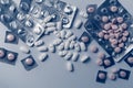 Top view of many prescription drugs, medicine tablets or vitamin pills in a pile and empty blister packs in blue color tone