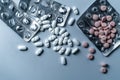 Top view of many prescription drugs, medicine tablets or vitamin pills in a pile and empty blister packs on clean white background